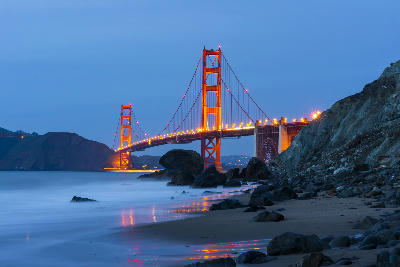 Golden Gate Bridge at night from Baker Beach with reflections and blue sky in San Francisco