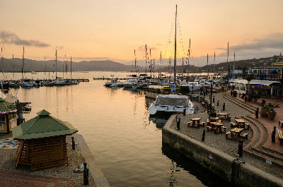 Boats and marina facilities on Knysna Lagoon at sunset with calm water and surrounding hills in Knysna, South Africa.