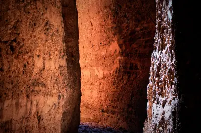 Sunlight penetrates the narrow walls of Echidna Chasm, creating a vivid orange glow on the towering sandstone cliffs.