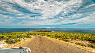 Winding Cape du Couedic Road descending through coastal heathland towards the Casuarina Islets and Southern Ocean on Kangaroo Island, South Australia.