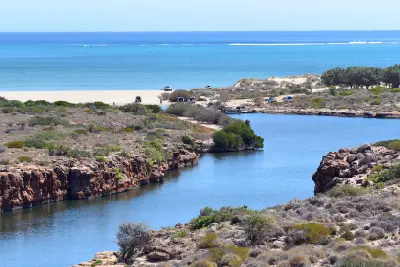Yardie Creek winds between red limestone cliffs toward the turquoise waters of the Ningaloo coast.