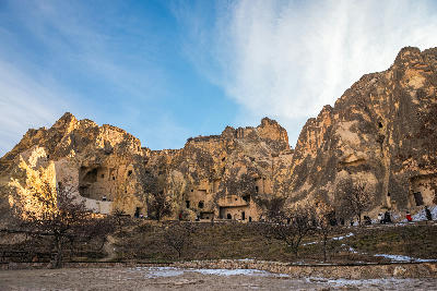 Rock-cut churches and cave monasteries at Göreme Open Air Museum in Cappadocia, Turkey, carved into towering volcanic cliffs beneath a blue sky.