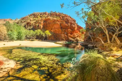 Turquoise water beneath red cliffs and river gums at Ellery Creek Big Hole.