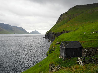 Coastal cliffs and turf-roof shed near Mikladalur on Kalsoy, Faroe Islands.