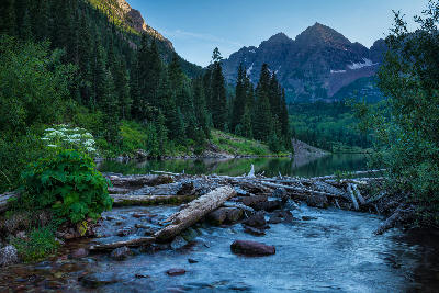 Foreground stream and logs leading toward Maroon Bells at Maroon Lake Aspen Colorado