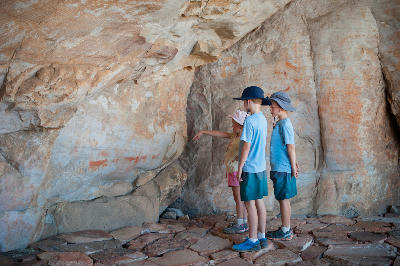 Children viewing San rock art paintings inside a sandstone shelter along the Sevilla Rock Art Trail in the Cederberg Mountains, Western Cape, South Africa.