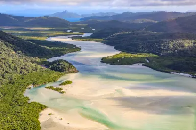 Aerial view of Hill Inlet with winding turquoise channels, pale sandbanks and forested hills on Whitsunday Island, Queensland.