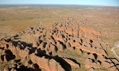 Sweeping aerial view of the striped sandstone formations of the Bungle Bungle Range surrounded by the vast Purnululu wilderness.