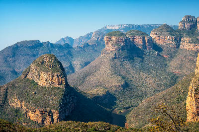 The Three Rondavels rock formations overlooking Blyde River Canyon in Mpumalanga, South Africa, with layered mountains and canyon valleys stretching into the distance.