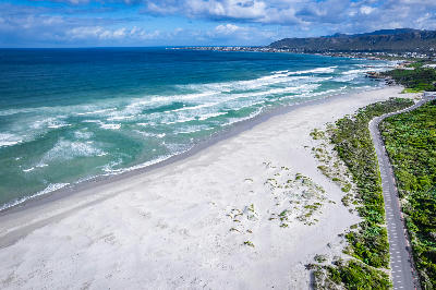 Aerial panorama of Grotto Beach in Hermanus showing tidal estuary patterns, white sand beaches, turquoise ocean waves, and coastal dune systems along the Overberg Whale Coast in South Africa.