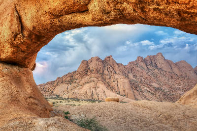 Granite rock arch framing the Spitzkoppe mountain formations in the Namib Desert of Namibia.