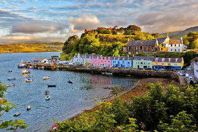 View over Portree on the Isle of Skye before sunset, with harbour, colourful buildings, and soft evening light.
