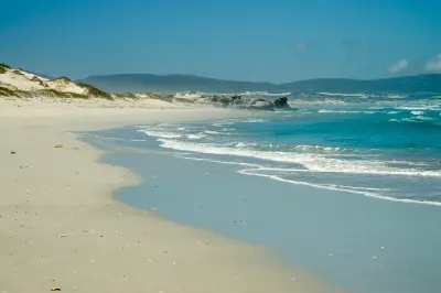 Wide sandy shoreline and turquoise surf along Grotto Beach in Walker Bay near Hermanus, South Africa