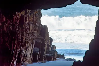 View from inside Remarkable Cave through the rocky opening toward breaking ocean waves in Tasmania.