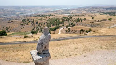 Ancient eagle sculpture at Karakuş Tumulus overlooking dry hills, farmland and the distant Euphrates landscape in Adıyaman, Turkey.