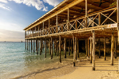 Wooden beachfront restaurant on stilts overlooking the turquoise Indian Ocean at Nungwi Beach during golden hour, Zanzibar, Tanzania.