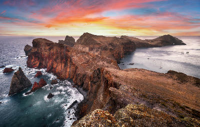 Sunset over the rugged cliffs and windswept ridge of Ponta de São Lourenço, Madeira, with volcanic headlands dropping into the Atlantic Ocean and calm waters along the eastern peninsula.