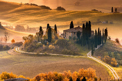 Podere Belvedere farmhouse surrounded by cypress trees in the Val d'Orcia hills of Tuscany, Italy.