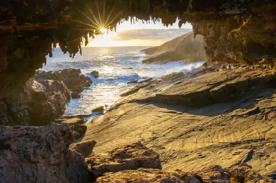 Golden sunlight shining through Admirals Arch above the rocky Southern Ocean coastline on Kangaroo Island, South Australia.