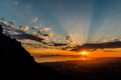 Golden sunset over False Bay from Sir Lowry’s Pass with sunbeams above Strand and the Cape coastline silhouetted beneath dramatic clouds in the Western Cape, South Africa.