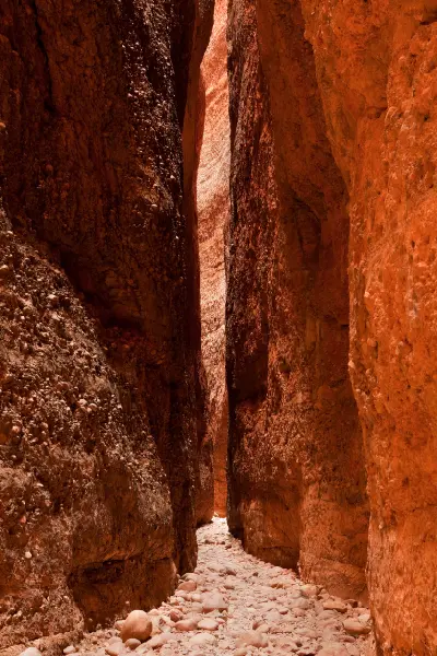 Towering orange rock walls form a narrow passage above the rocky floor of Echidna Chasm in the Bungle Bungles.