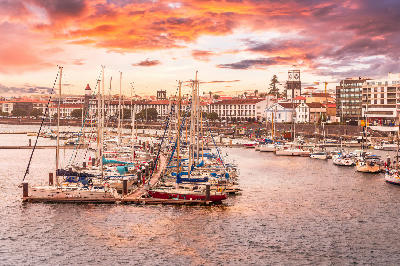 Yachts moored in Ponta Delgada Marina with the historic waterfront and church tower in the background on São Miguel Island, Azores.
