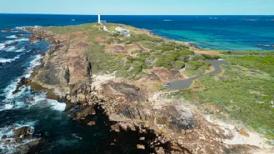 Aerial view of Cape Leeuwin Lighthouse rising above the rocky headland and surrounding ocean.