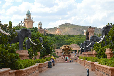 Bridge of Time walkway lined with elephant statues leading toward the Palace of the Lost City at Sun City, South Africa.