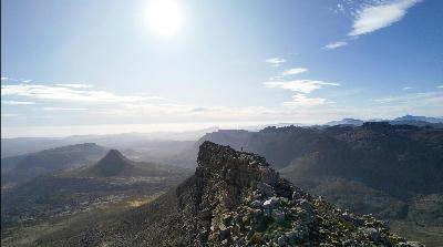 Hiker standing on the summit ridge of The Pup overlooking vast mountain valleys and rugged wilderness landscapes in the Southern Cederberg near Kromrivier, Western Cape, South Africa.