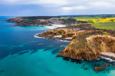 Aerial panorama of King George Beach on Kangaroo Island, South Australia, showing rocky coastal headlands, turquoise ocean water, sandy coves and green farmland inland.