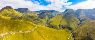 Aerial view of the winding Outeniqua Pass crossing the green mountain ridges of the Outeniqua Range near George in South Africa.