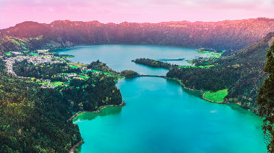 Twin lakes of Lagoa das Sete Cidades filling a volcanic crater, with turquoise and blue waters surrounded by forested caldera walls on São Miguel Island, Azores.