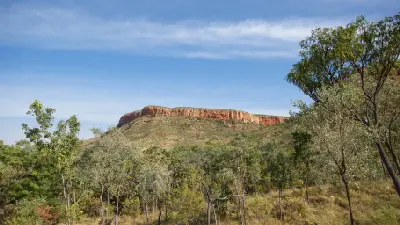 Red sandstone escarpment of the Cockburn Range rising above eucalyptus woodland in the Kimberley.