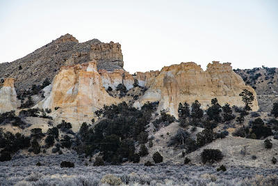 Sandstone cliffs and eroded formations rising from a desert hillside in Grand Staircase–Escalante National Monument, Utah.