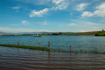 Yacht moored on Midmar Dam with rolling hills and open countryside in the KwaZulu-Natal Midlands.