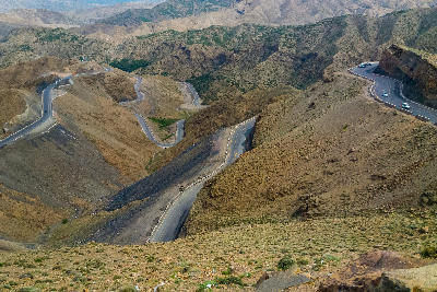 Steep winding roads crossing rugged mountain terrain near Tizi n'Tichka Pass in the High Atlas Mountains of Morocco.