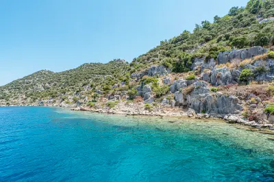 Rocky, undeveloped coastline of Kekova Island in Antalya, Turkey, bordered by clear turquoise Mediterranean water.