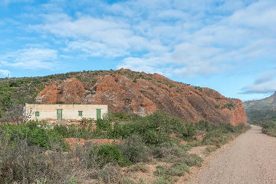 Red sandstone hills and rural farm landscape along a gravel road in the Red Stone Hills area of the Klein Karoo in South Africa’s Western Cape