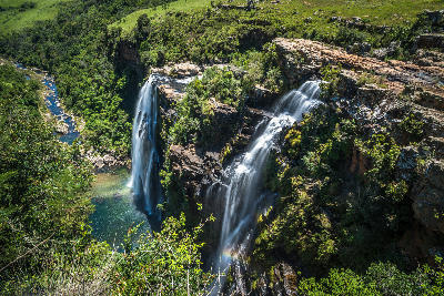 Lisbon Falls in Mpumalanga, South Africa, showing twin waterfalls plunging into a rocky gorge and emerald pool along the Panorama Route.