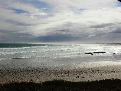 Moody coastal landscape at Sixteen Mile Beach with dark clouds, sea mist, wet sand and wind-driven Atlantic surf near Yzerfontein.