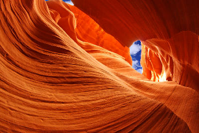 Lower Antelope Canyon in Arizona showing curved sandstone walls with layered textures and warm orange light, viewed from inside the narrow slot canyon looking upward.