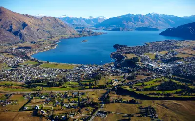 Aerial panorama of Wanaka town and Lake Wanaka with surrounding mountains of the Southern Alps in New Zealand.