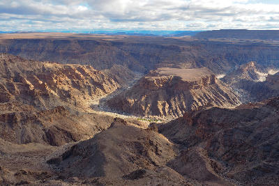 Wide elevated view across Fish River Canyon in Namibia showing layered canyon walls, plateaus, and the winding river channel below.