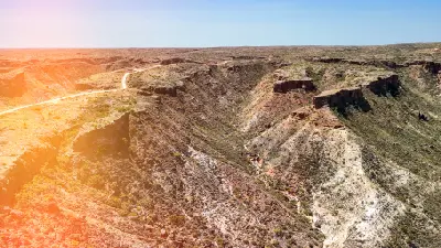 Aerial view of a winding road crossing the rugged ridges and deep gullies of Charles Knife Canyon.
