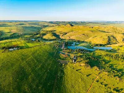 Aerial view of the Cradle of Humankind showing green agricultural fields, small lakes and rocky hills stretching across a broad valley northwest of Johannesburg, South Africa.