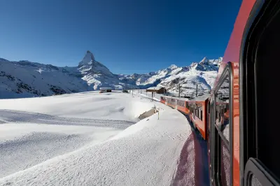 Gornergrat Railway train traveling through snowy alpine terrain with the Matterhorn visible in the distance near Zermatt
