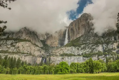 Yosemite Falls flowing down granite cliffs in Yosemite Valley, showing the upper and lower sections of the waterfall in Yosemite National Park, California.