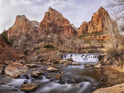 Court of the Patriarchs cliffs above the Virgin River with small waterfall, rocks, and footbridge in Zion National Park, Utah.