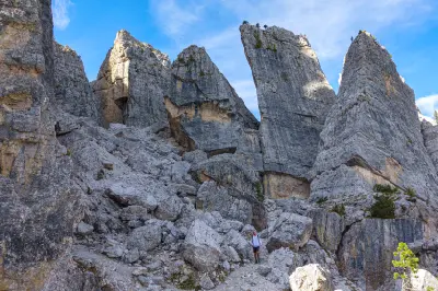 Rock towers of Cinque Torri rising among alpine terrain in the Dolomites, with views toward Lagazuoi and the Tofane range in the background, Italy.