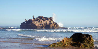 Castle Rock sea stack offshore from Brenton-on-Sea with waves breaking around the sandstone formation near Knysna, South Africa.